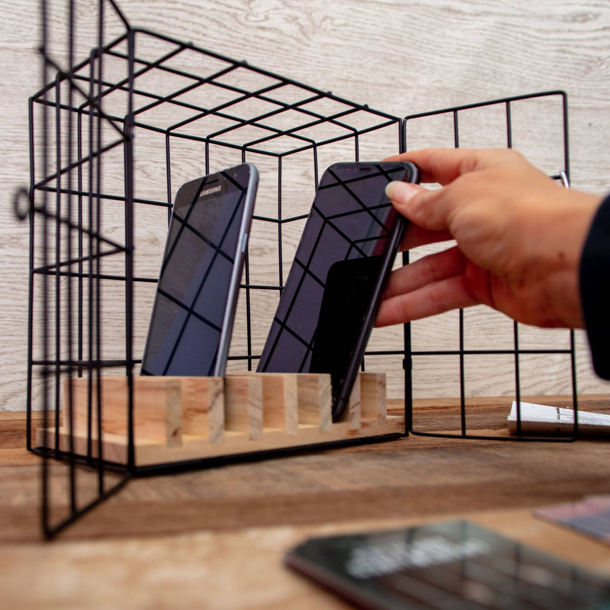 Metal lock cage with two phones being placed by hand for puzzle play