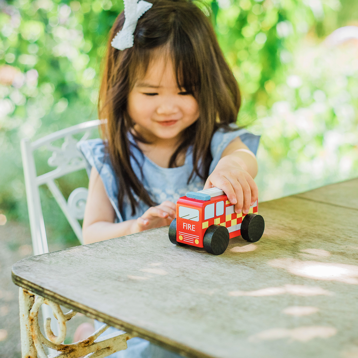 Wooden fire engine toy on a table, red cab with checkered details and large black wheels