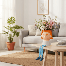 Flower bouquet in an orange hat planter figure with dangling legs and blue shoes
