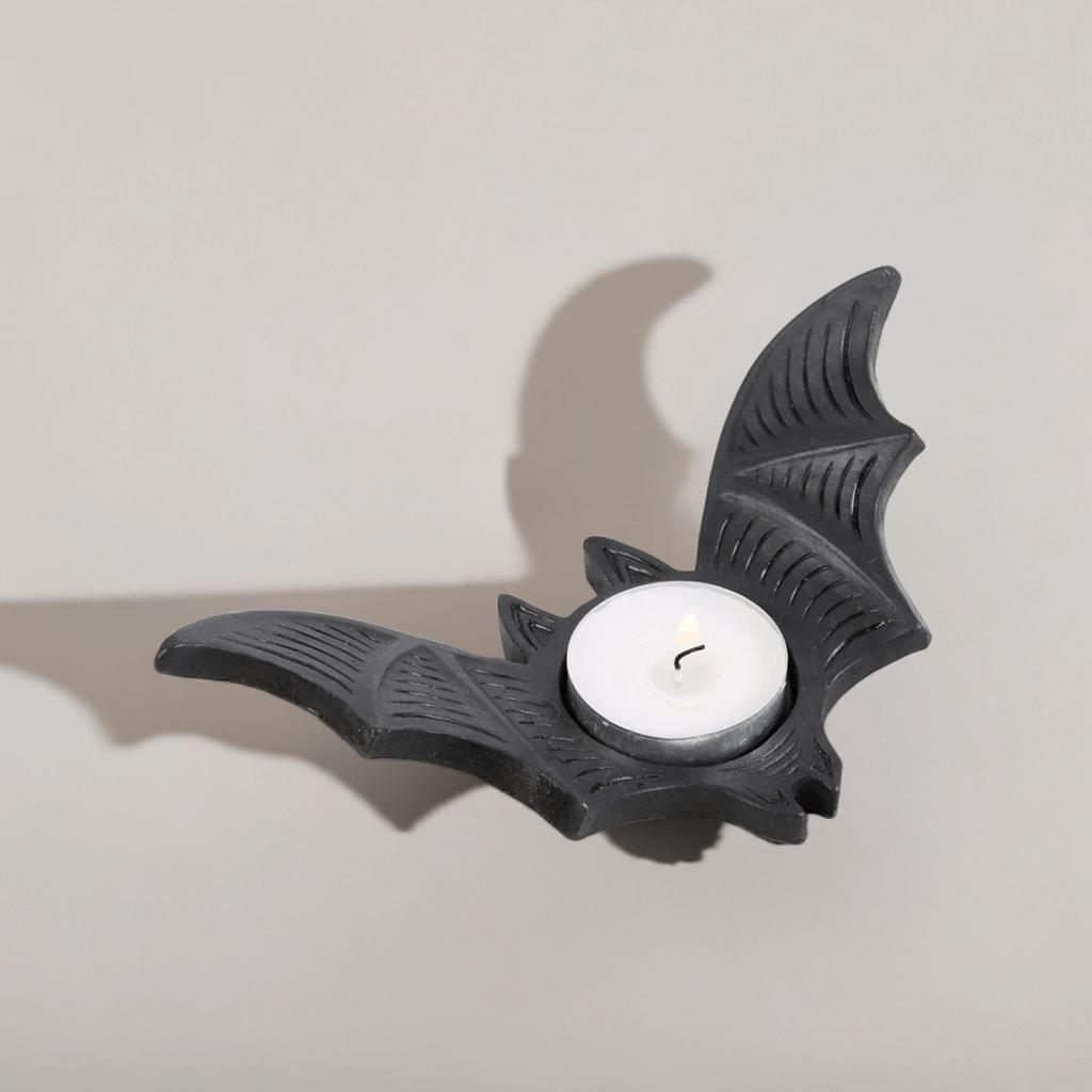 Bat-shaped tealight candle holder with white candle and wick, matte black finish.