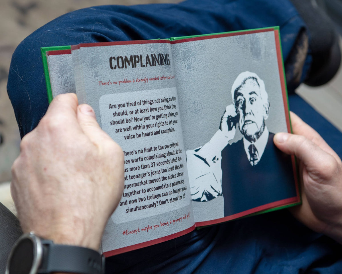 Open book showing page titled “COMPLAINING” with an old man illustration