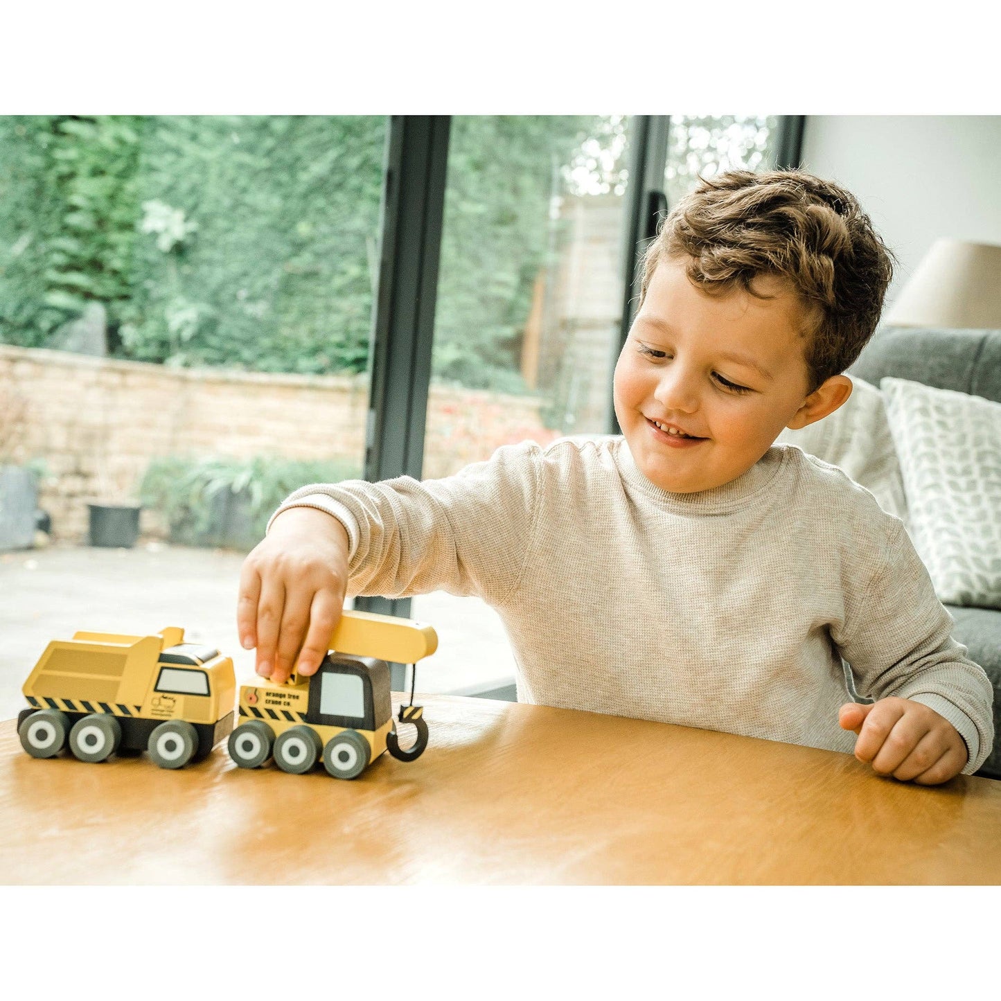 Yellow construction truck toys on table as a child plays with them