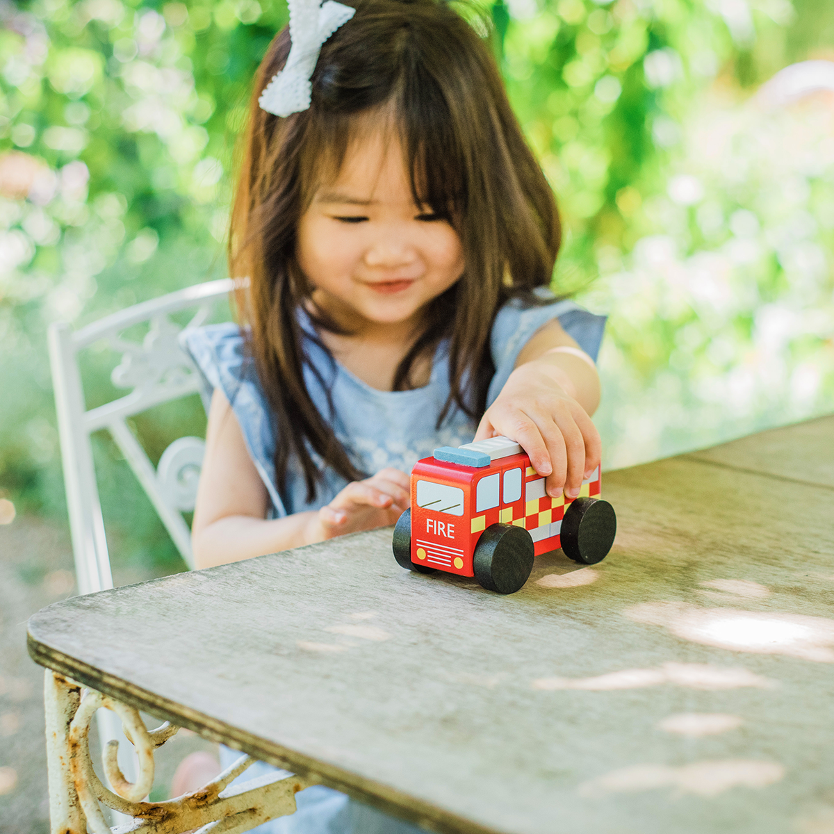 Wooden fire engine toy on a table, red cab with checkered details and large black wheels