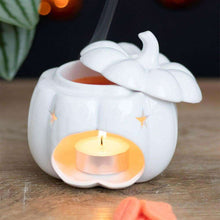 White ceramic pumpkin wax melt burner with star cutouts and lit tealight in bowl